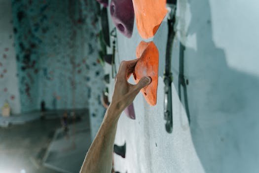 A close-up view of a hand gripping holds on an indoor climbing wall, showcasing strength and technique.