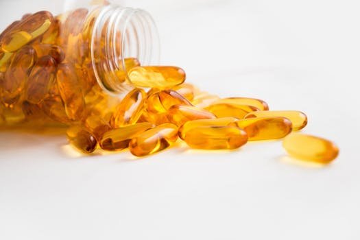 Close-up of fish oil capsules spilling from a bottle on white background. Best supplements for muscle growth