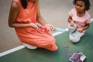 Two children playing with a balloon pump and balloons on an outdoor yard. for football pumps page