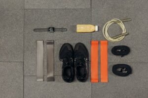 Flat lay of workout essentials including sneakers, bands, watch, rope, and healthy drink. For finess resistance bands page