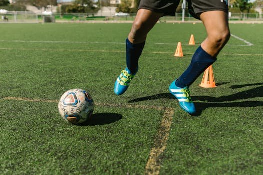 Dynamic image of a soccer player practicing drills on a grass field with vibrant shoes and cones. For the page Football drills at home