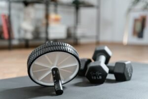 Ab roller and dumbbells on yoga mat, perfect for a home workout routine and healthy lifestyle. For fitness accessories page